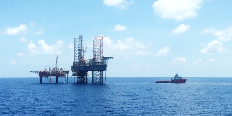 Oil and gas platform with offshore vessel transporting cargo