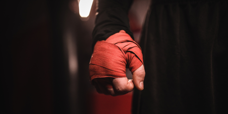 One man, kickboxer with wrapped boxing bandages on hand.