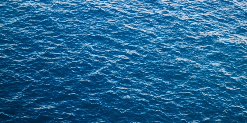 Blue sea with ribbed textured waves, top view. Mediterranean Sea in Italy, copy space
