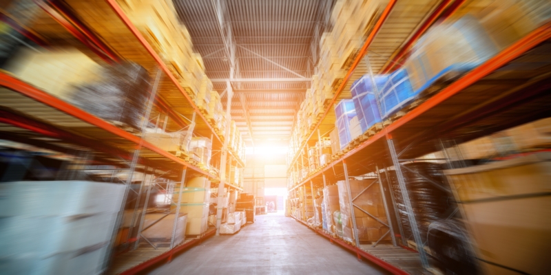 Warehouse industrial and logistics companies. Long shelves with a variety of boxes and containers. Motion blur effect. Bright sunlight.