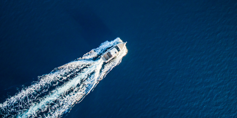 Fast speedboat racing along the open sea leaving white trail. High angle view from drone (quadcopter) Phantom 3.