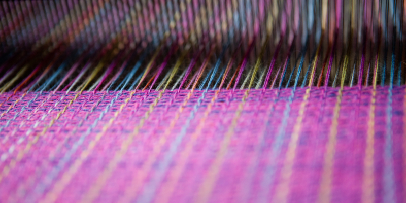 Close up detail shot of weaving being done on a traditional Ecuadorian loom.